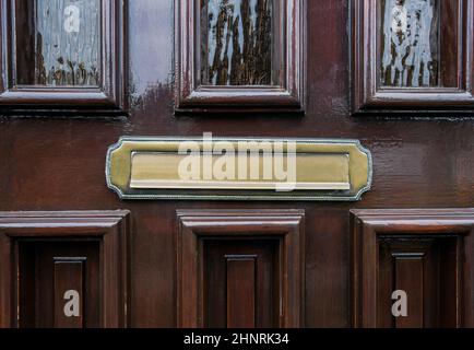 Front door of dark brown wood with traditional gold colored mailbox antique design Stock Photo