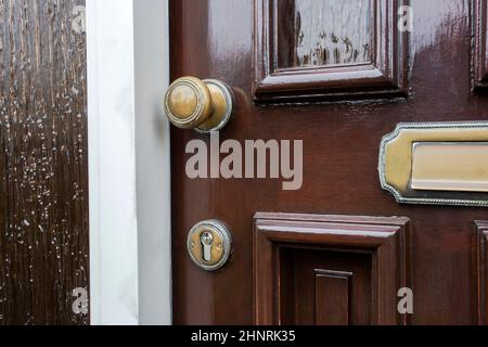 Front door of dark brown wood with traditional gold colored mailbox antique design Stock Photo