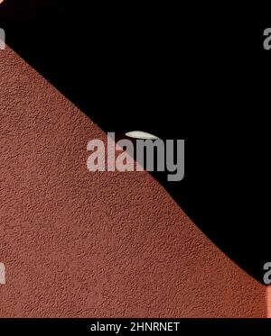 abstract design of shadows on exterior of home or building textured concrete or cement wall with tiny light shining in the triangular shaped shadow ge Stock Photo