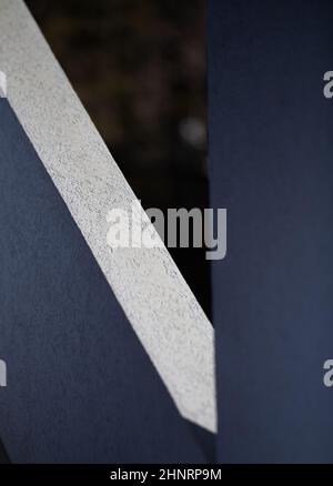 abstract design of shadows on grey white exterior wall of building creating geometrical shapes in black and white angles and lines vertical backdrop Stock Photo
