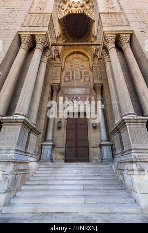 Bricks stone wall with arabesque decorated wooden door and marble engraved columns, al Refai Mosque Stock Photo