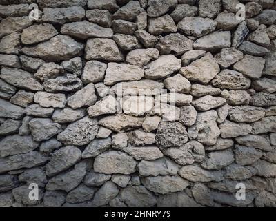 Irregular stone masonry wall background. Old limestone rocks of different size and shapes stacked carefully. Detailed texture of construction element. Stock Photo
