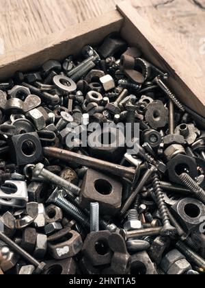 Old rusty bolts and nuts in a wooden box on a workbench Stock Photo