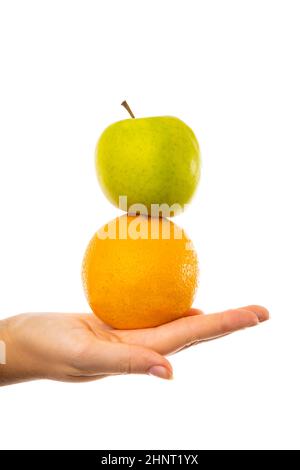 Comparison of apples with oranges. Young female woman holding an apple and an orange in her hand. Stock Photo