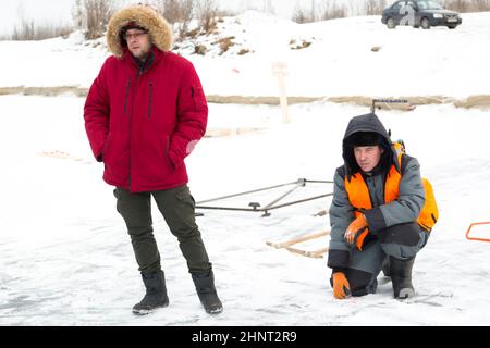 Fitters in winter gear are having a conversation on the ice of a frozen lake Stock Photo