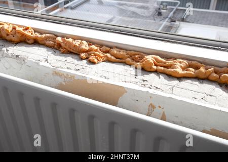 Worker using a polyurethane foam for installation of window sill. Installing window sill restoration,renovation house,building close-up Stock Photo