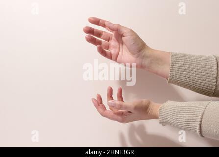 two female hands hold any object on a beige background. Product presentation, cosmetics Stock Photo