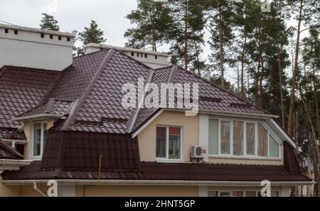 Roof on residential property with new brown corrugated metal roof tiles. Modern metal roof. Metal roofing. Stock Photo