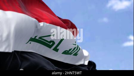 Detail of the national flag of Iraq waving in the wind on a clear day. Democracy and politics. Patriotism. Western asian country. Selective focus. Stock Photo