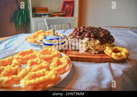 Chocolate cake with cherries, grated chocolate and whipped cream. Homemade cream puffs on festive table. Vintage sugar bowl. Close-up. Kitchen background. Low DOF Stock Photo