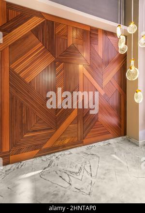 Wood cladding wall, modern glass tall chandelier, and white marble floor Stock Photo