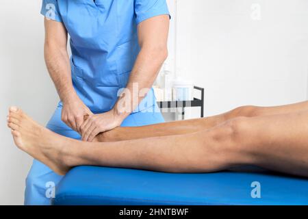 Close-up of therapist massaging young man's foot Stock Photo