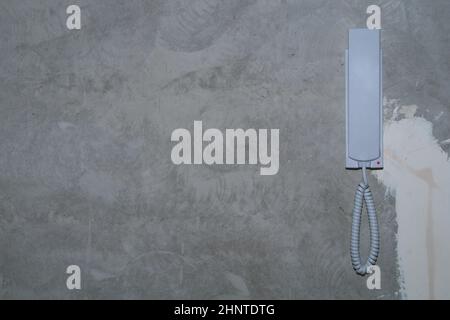 Intercom phone receiver on gray concrete background. handset on the wall close up Stock Photo