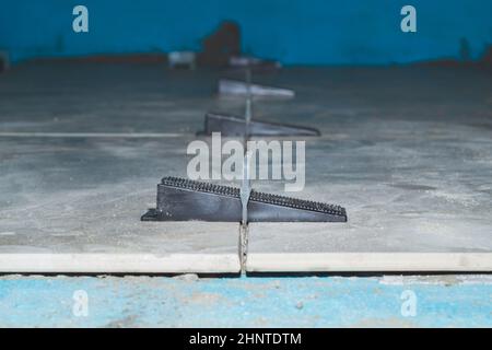 Tile leveling system. plastic clips for laying granite tiles on the floor close up Stock Photo