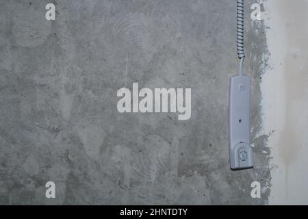 Intercom phone receiver on gray concrete background. handset hanging on the wire close up Stock Photo