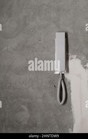 Intercom phone receiver on gray concrete background. handset on the wall close up Stock Photo