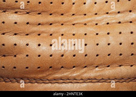 Brown leather texture with holes and stitches. creased material with seams macro background Stock Photo