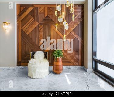 Modern white feather armless chair, tall wooden plant pot, decorated wood cladding wall, and big glass window Stock Photo