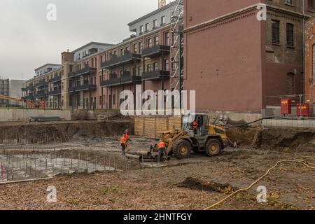 Construction workers loading old pipes on a large construction site Stock Photo