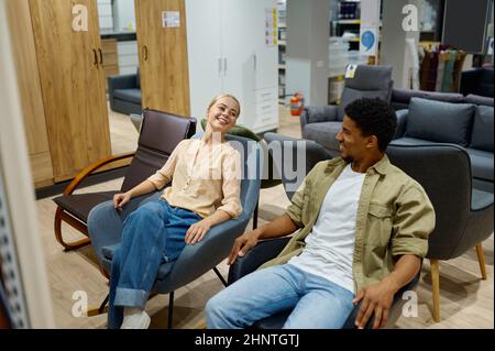 Multiracial couple on chair in furniture store Stock Photo