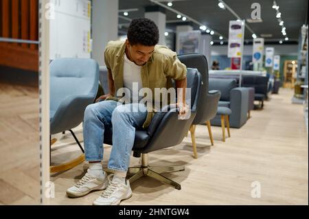 Young man choosing chair in furniture store Stock Photo