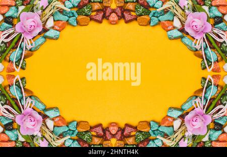 Festive decoration. candy pebbles on a yellow background. sweets in the form of colored stones. symmetrical frame made from colorful candies Stock Photo