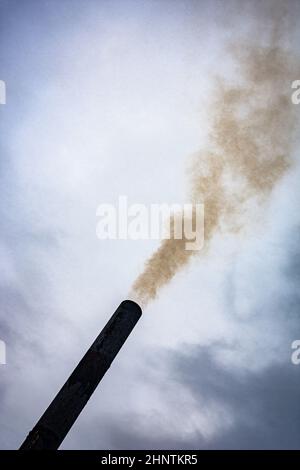 smoke from the chimney on the cloudly sky background colored Stock Photo