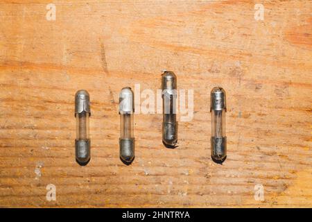 Row of fuses with burned out fuse on wooden background. safety device for overcurrent protection. protection of an electrical circuit Stock Photo