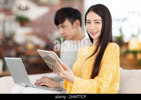 Young couple using laptop and tablet  in the living room. Stock Photo