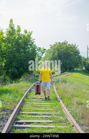 happy man with suitcase walking on the railroad Stock Photo