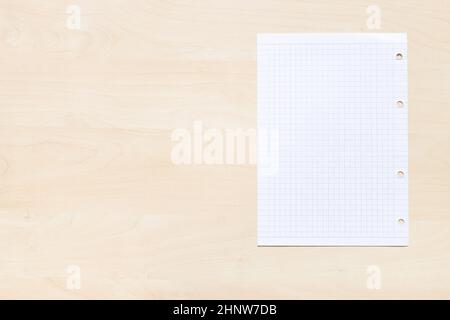 top view of blank sheet of squared paper on light brown wooden board with copyspace Stock Photo