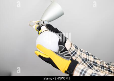 electrician removing bulb from fault ceiling light at home Stock Photo