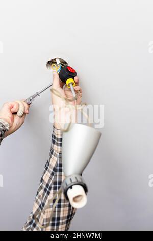 man disassembles defected ceiling lamp at home Stock Photo