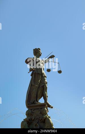 Lady justice at the Roemer in Frankfurt am Main symbolizes Justice with sword and scales under blue sky. Stock Photo