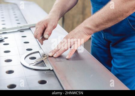 Metalworker using folding rule to measure steel strip for later cutting Stock Photo
