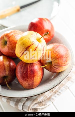 Fresh autumn apples on plate on white table. Stock Photo