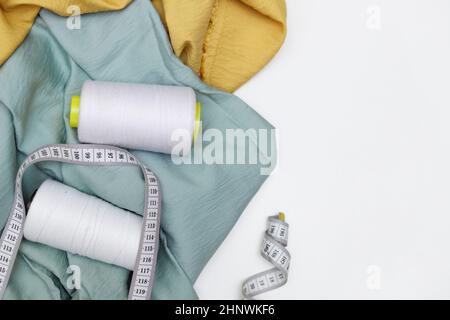 Various fabrics, measuring tape and thread isolated on white. Flat lay Stock Photo
