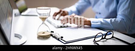 Late Invoice And Billing Deadline With Hourglass At Desk Stock Photo