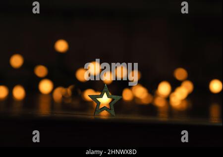 Small wooden sar shape against blurred Christmas lights Stock Photo