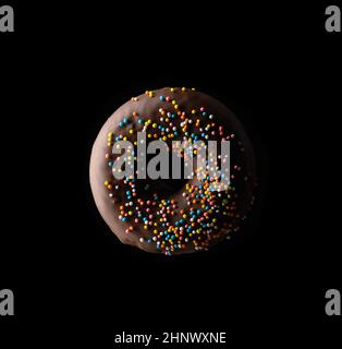 chocolate donuts with multicolored sprinkles levitate on a black background Stock Photo