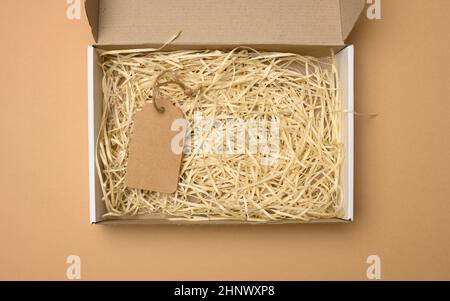 empty rectangular open corrugated paper box with sawdust inside. Packaging, containers for transportation on a brown background Stock Photo