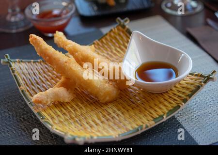 Shrimps tempura with soy sauce on yellow bamboo plate. Seafood tempura dish of traditional asian cuisine Stock Photo