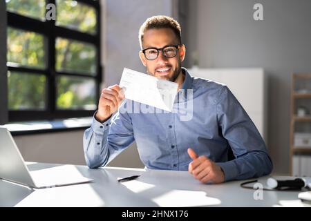 Holding Paycheck Or Payroll Check Or Insurance Cheque In Hand Stock Photo