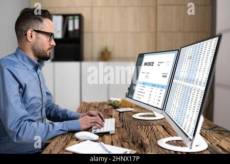 Looking At Invoice And Spreadsheet On Computer At Work Stock Photo