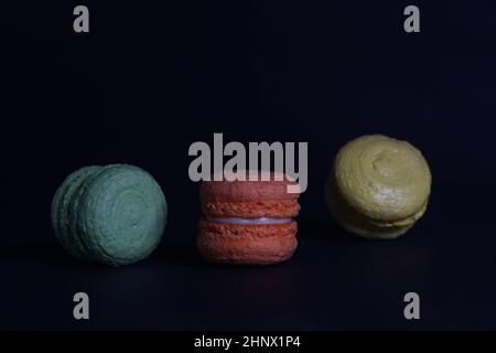 Sweet food concept - three macaroons isolated on black background. Image contains copy space Stock Photo