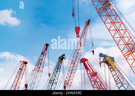 Crawler crane against blue sky and white clouds. Real estate industry. Red crawler crane use reel lift up equipment in construction site. Crane for re Stock Photo