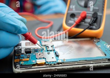 Technician repairing inside of mobile phone by soldering iron. Integrated Circuit. the concept of data, hardware, technology. Stock Photo