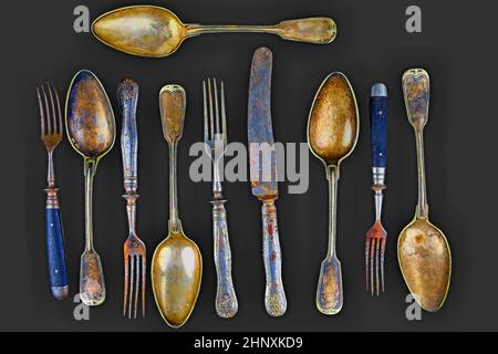 Vintage cutlery on a black background. Top view. Crazy concept for culinary and modern life. Contrast between shabby cutlery and excellent modern colo Stock Photo
