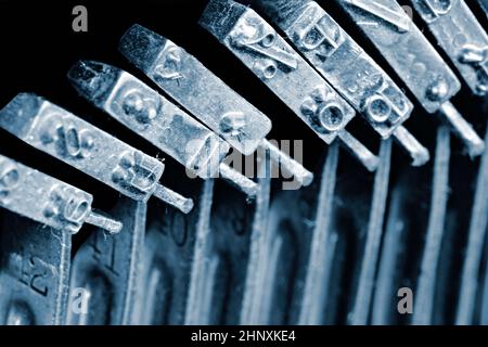 Detail of the individual hammers with engraved text and typescript inside vintage mechanical typewriter. Stock Photo