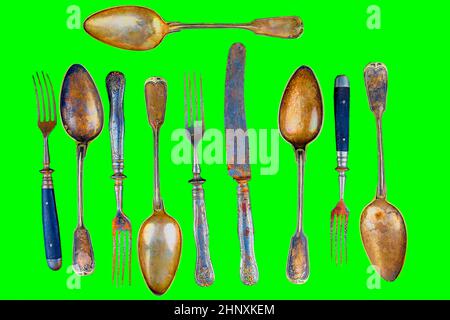 Vintage cutlery on a green background. Top view. Crazy concept for culinary and modern life. Contrast between shabby cutlery and excellent modern colo Stock Photo